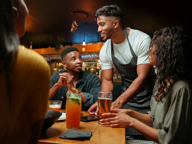Server chatting with a group of friends over drinks at their table